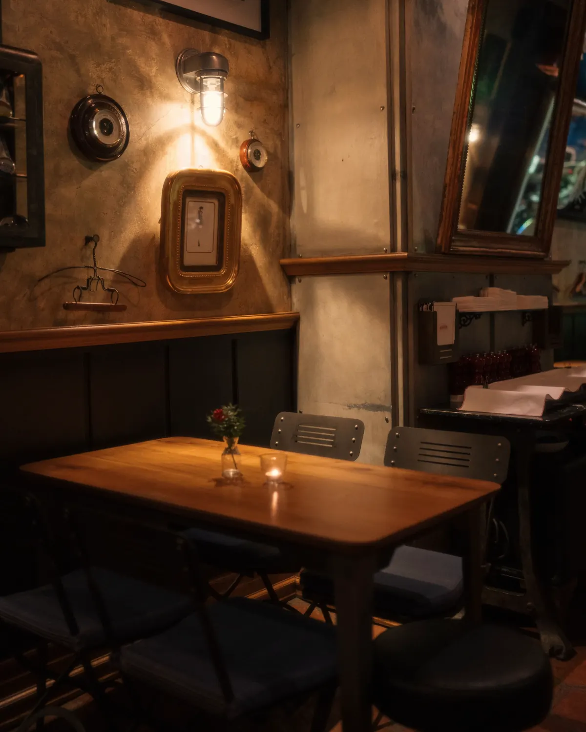 Hoek van het café met een houten tafel, lambrisering en een wandlamp